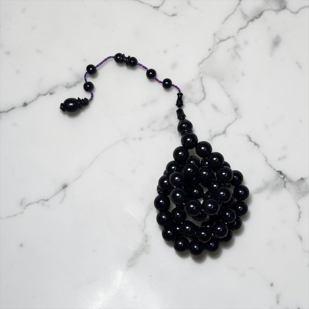 Miraj store handcrafted black Bakelite prayer beads with 51 polished 11mm beads and a decorative tassel on marble.
